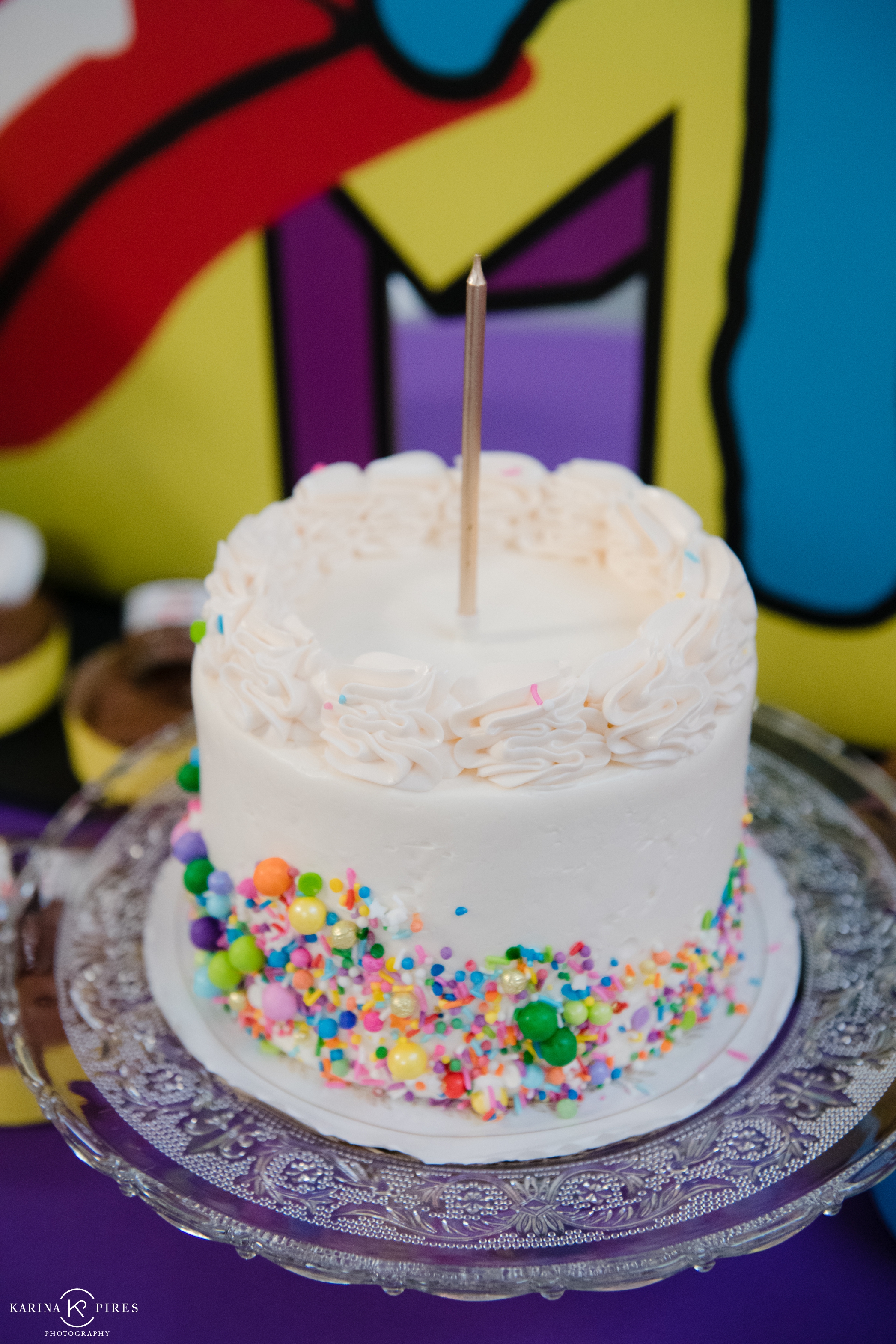 Single tier white cake, covered in lots of sprinkles and candy