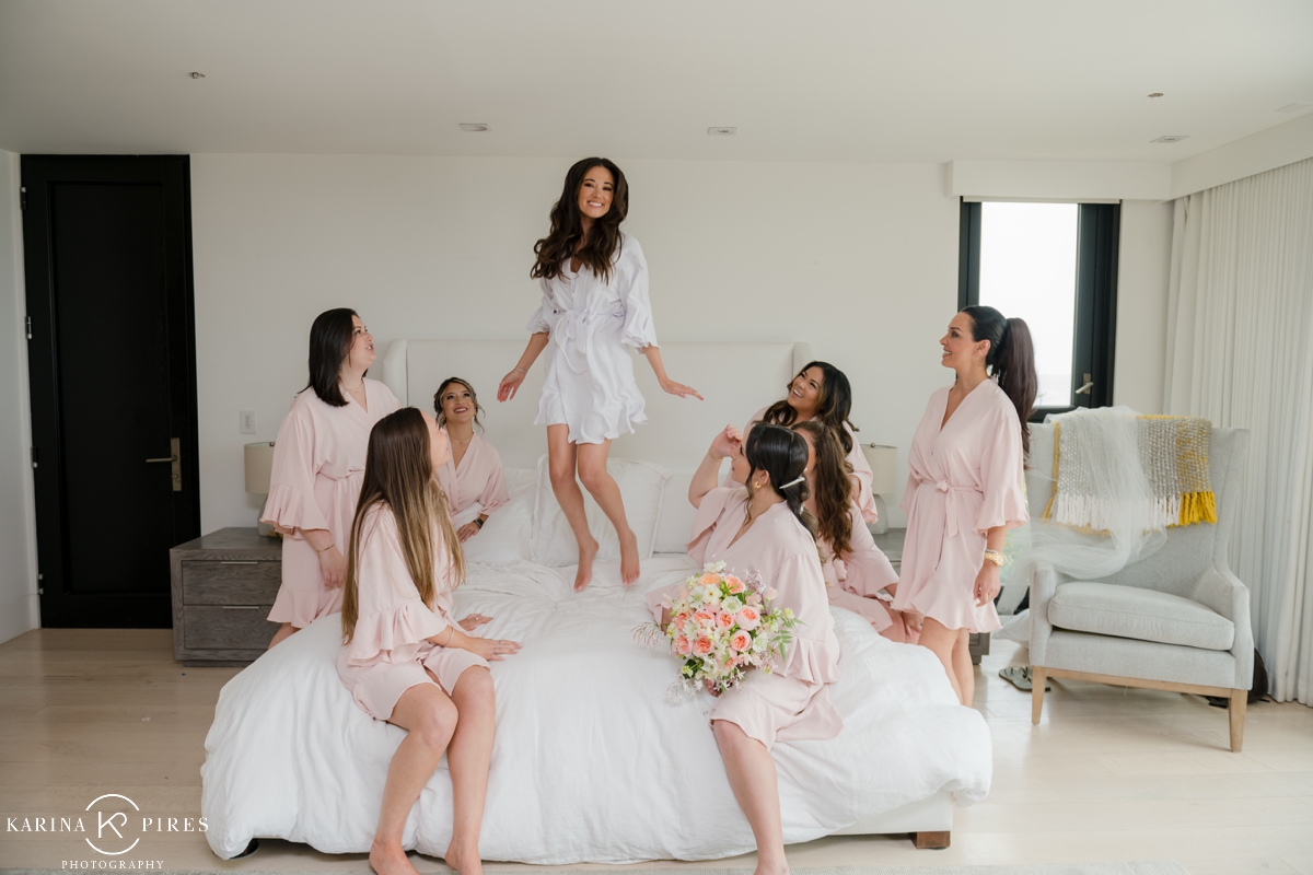 Bride and bridal party jumping on the bed