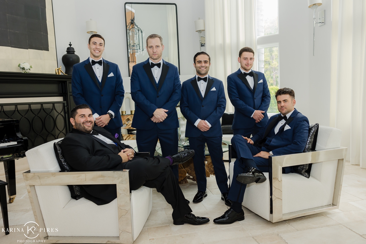 Groom in a black tuxedo, with groomsmen in navy tuxedos