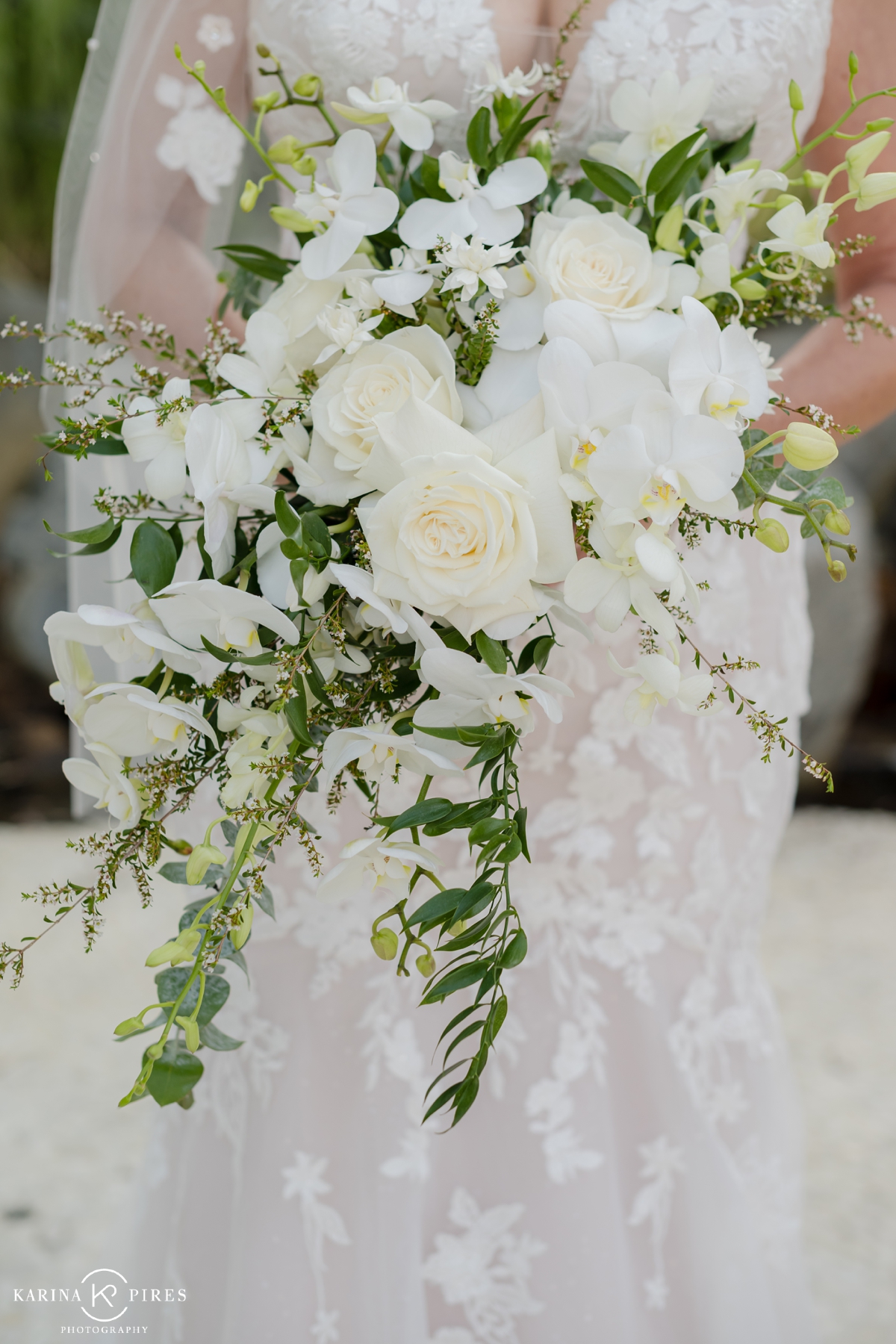 Bride holding a white bouquet filled with roses and orchids