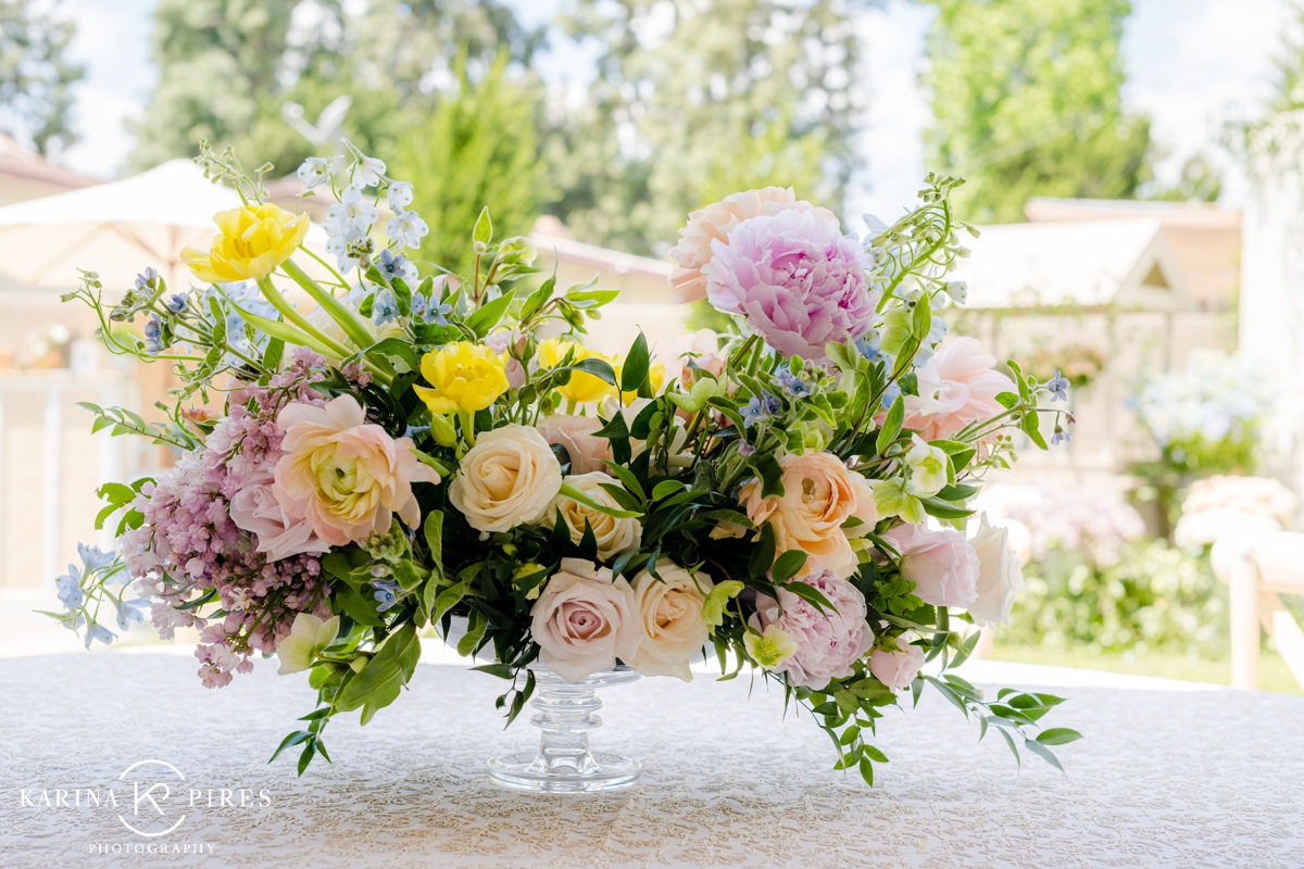 Floral centerpiece filled with peach roses, lavender carnations, and blue delphinium