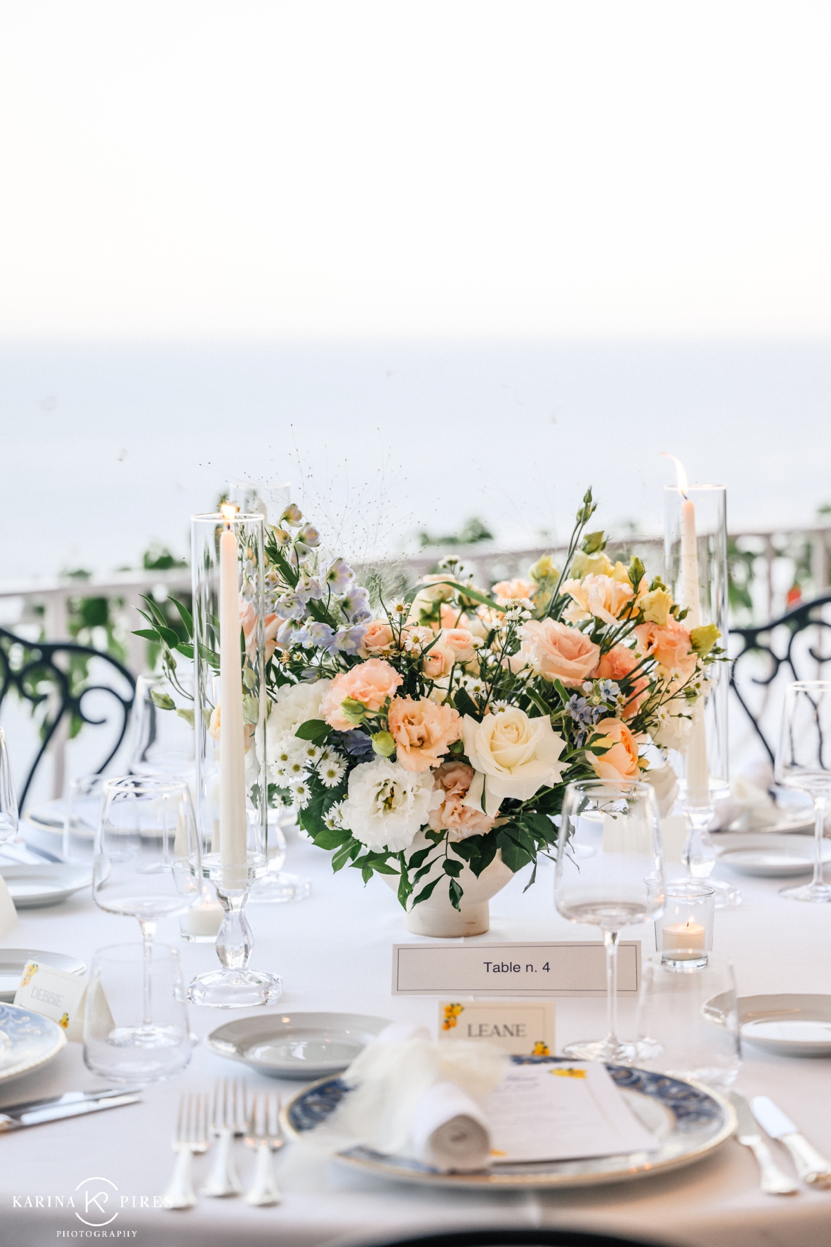 Floral centerpiece filled with delphinium, lisianthus, and roses at an outdoor wedding reception