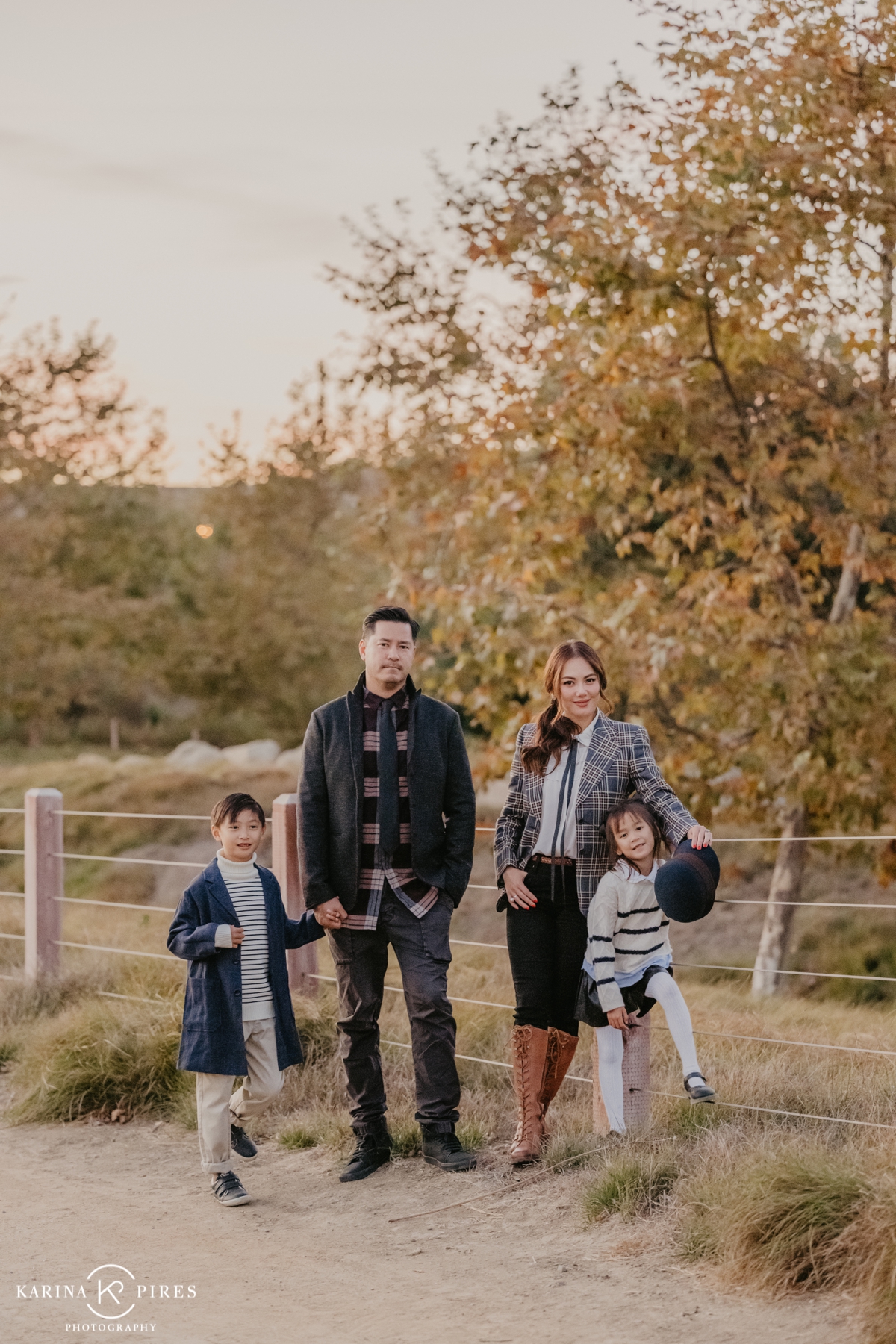 Family posing outdoors in Irvine, California, surrounded by vibrant fall leaves during a playful and candid session.