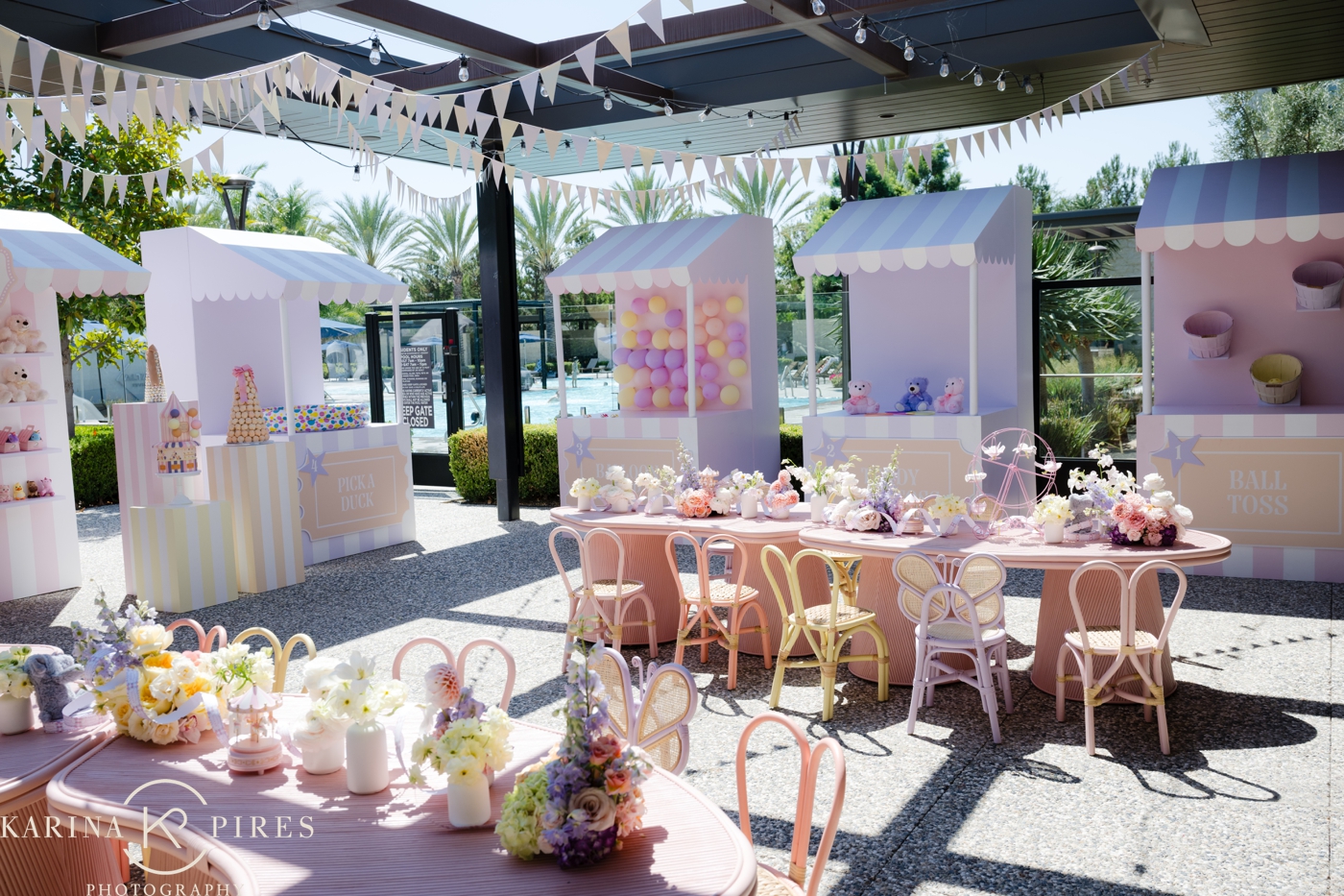 Curved reception tables decorated with pastel flowers, mini carousels, and pink ticket details