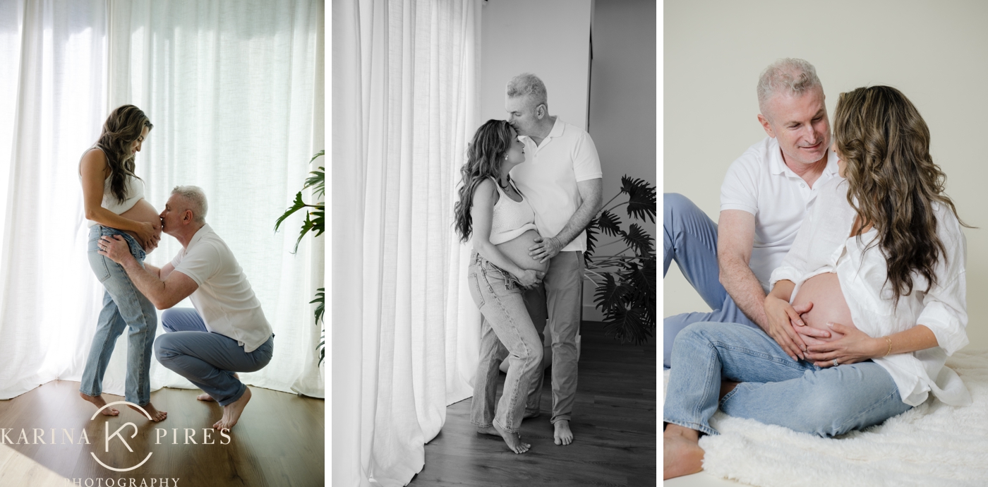 An expecting mother and her husband posing for a maternity session in their LA home, with sheer curtains behind them, both wearing light jeans and a white shirt